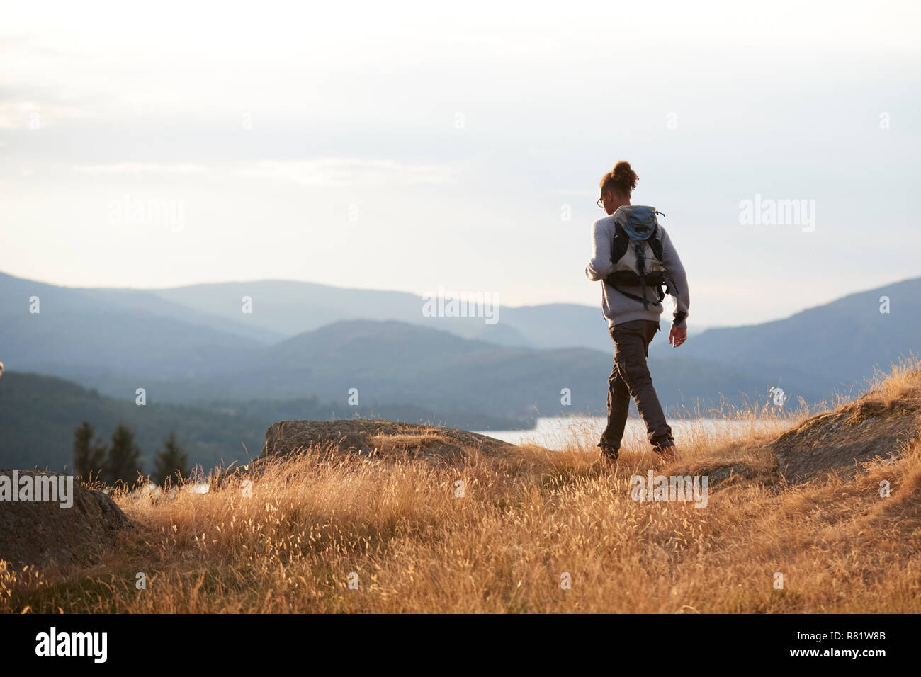 A young mixed race man hiking alone on a mountain peak, back view Stock Photo