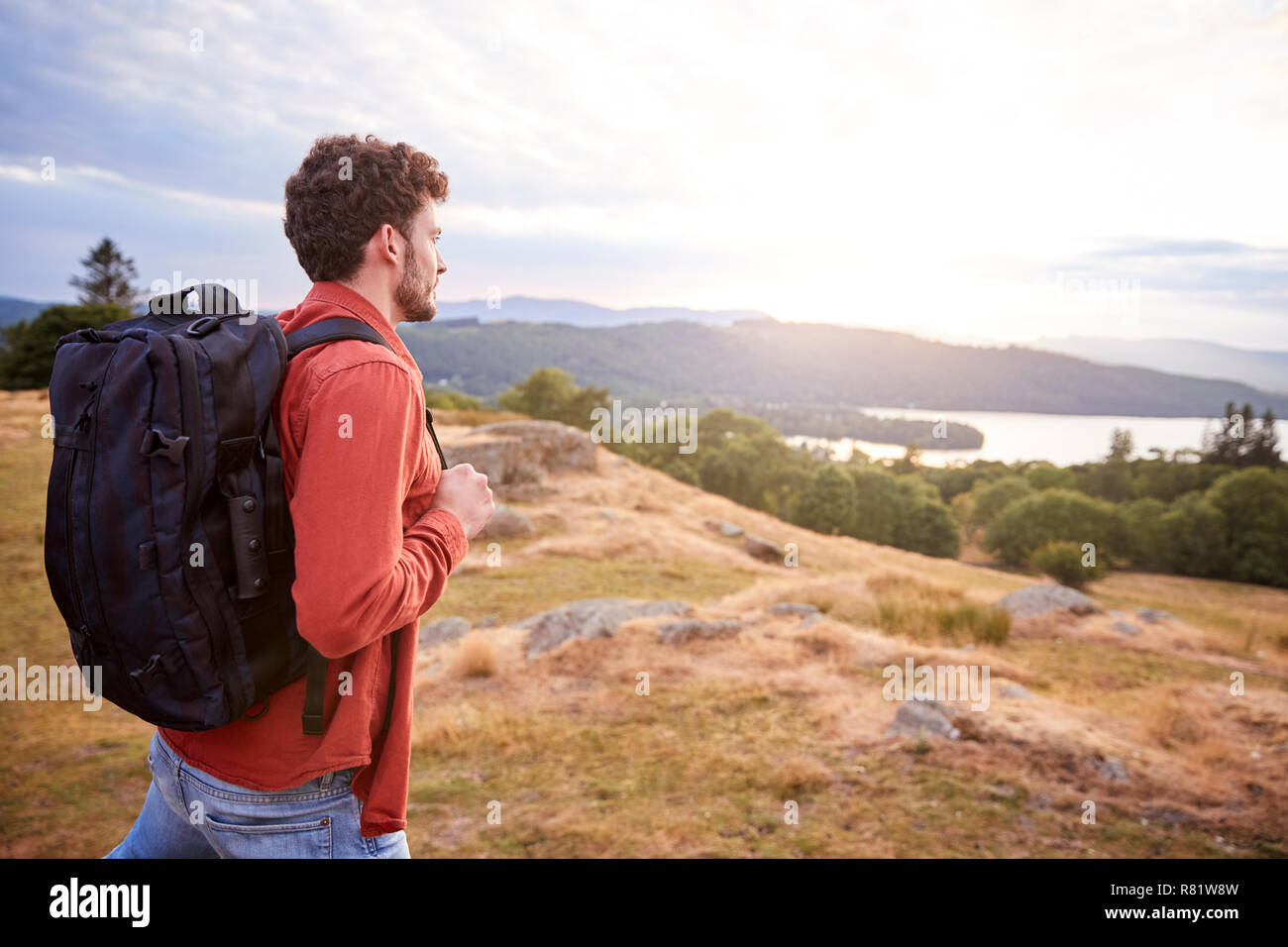 A young adult Caucasian man walking alone on a hill, admiring the view, side view Stock Photo