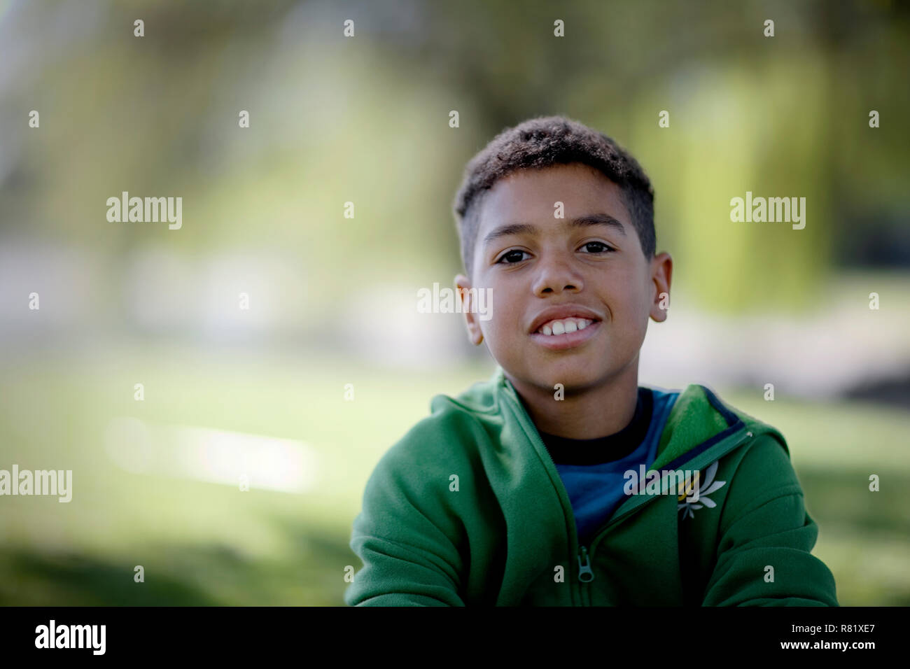 Portrait of a smiling boy sitting in a park Stock Photo - Alamy