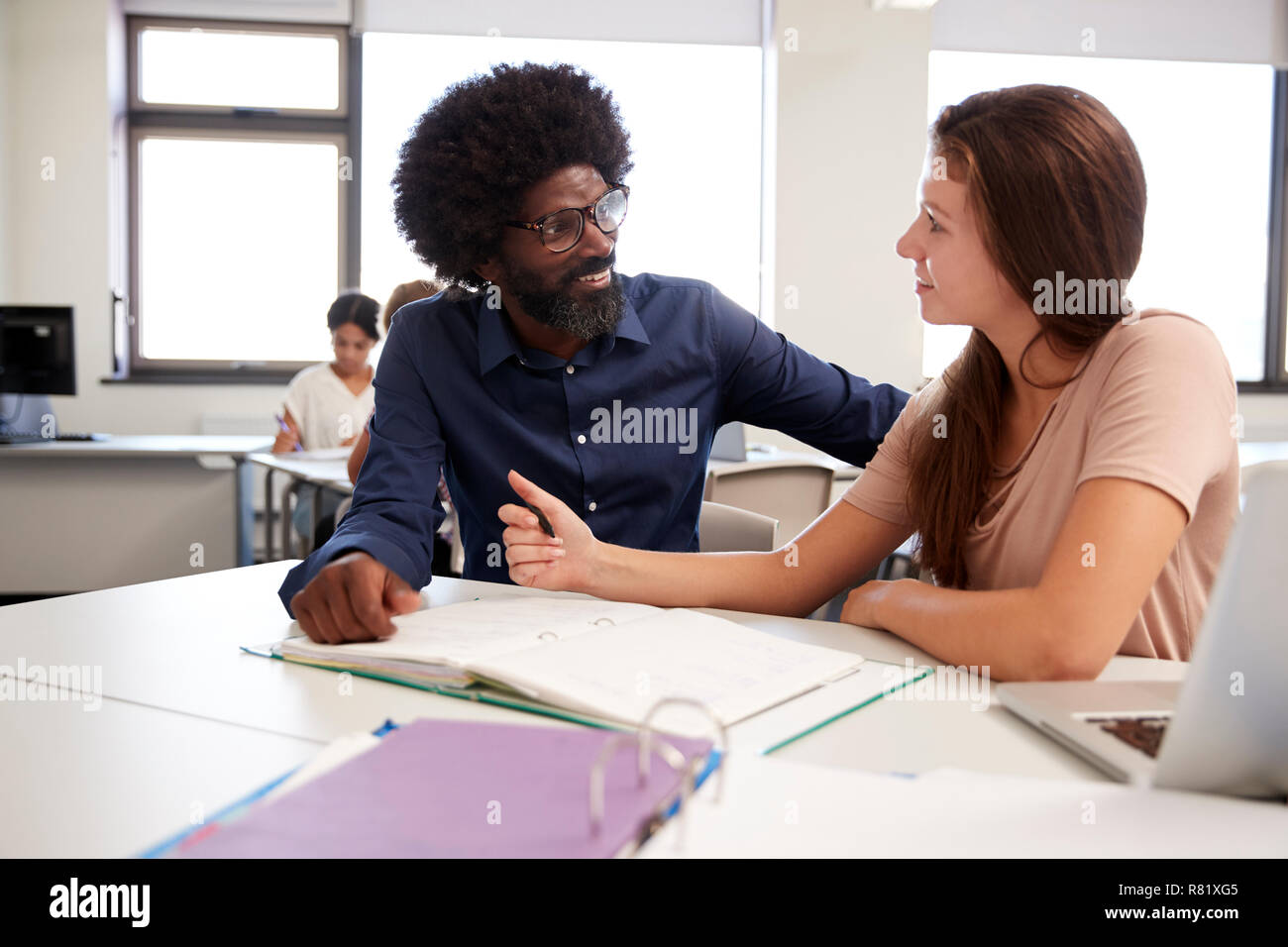 High School Tutor Giving Female Student One To One Tuition At Desk  In Classroom Stock Photo