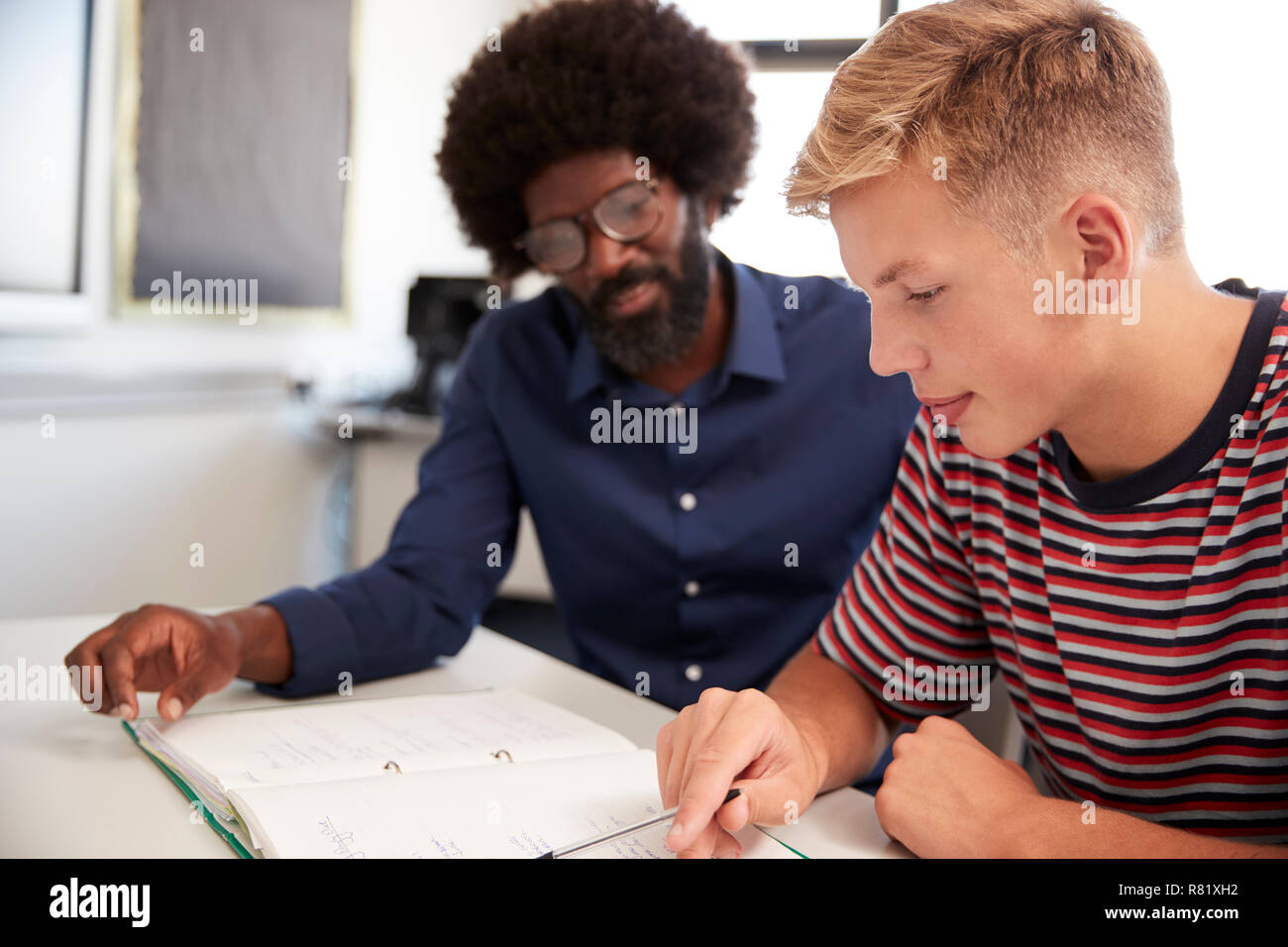 High School Tutor Giving Male Student One To One Tuition At Desk  In Classroom Stock Photo