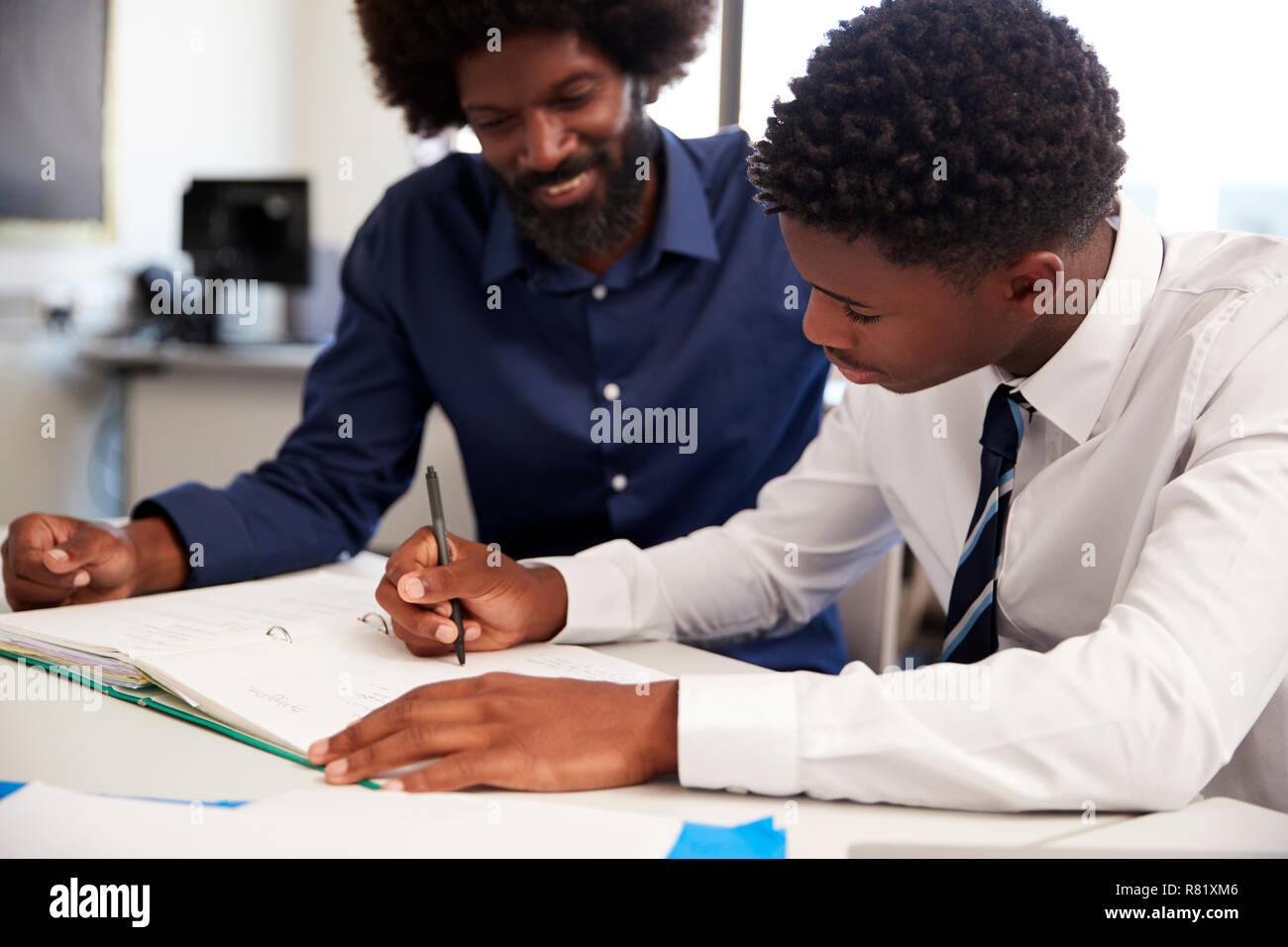 High School Tutor Giving Uniformed Male Student One To One Tuition At Desk In Classroom Stock Photo