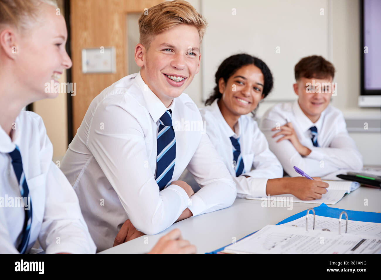 Line Of High School Students Wearing Uniform Sitting At Desk In Classroom Stock Photo
