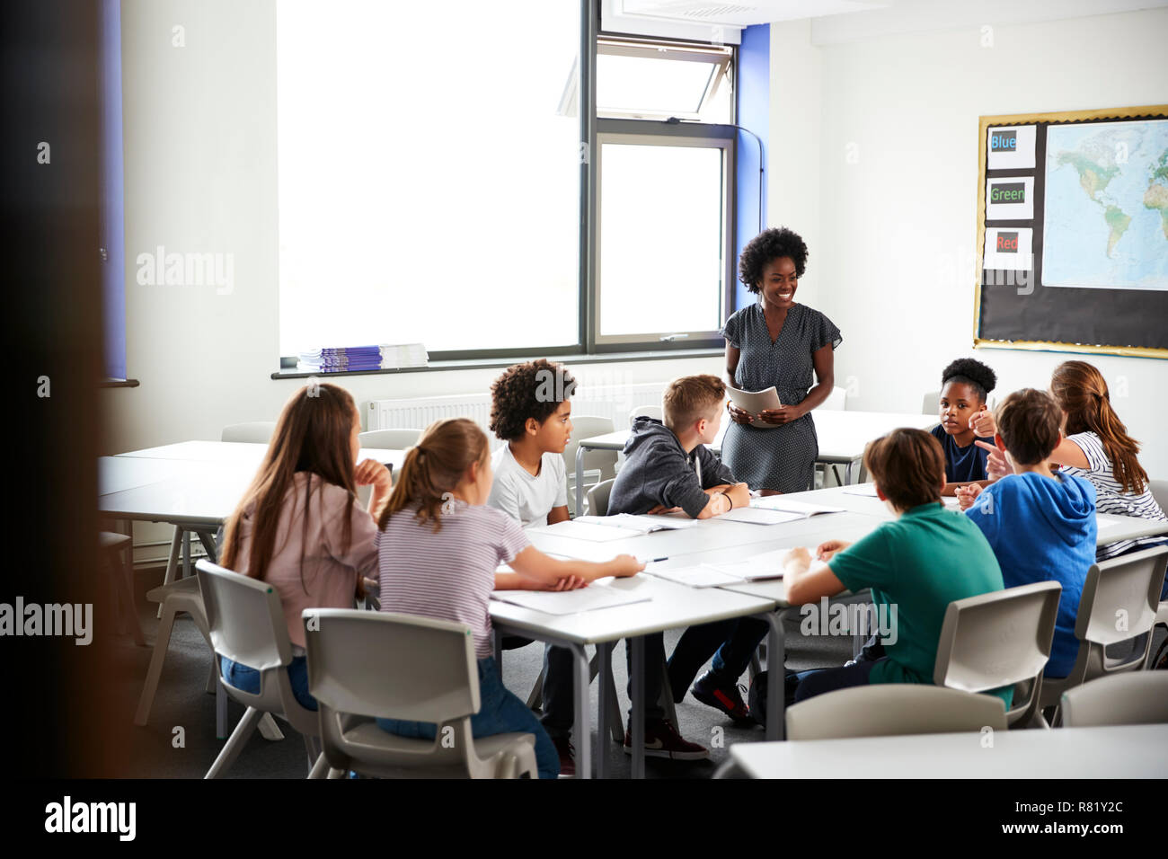 Female High School Tutor Standing By Table With Students Teaching Lesson Stock Photo