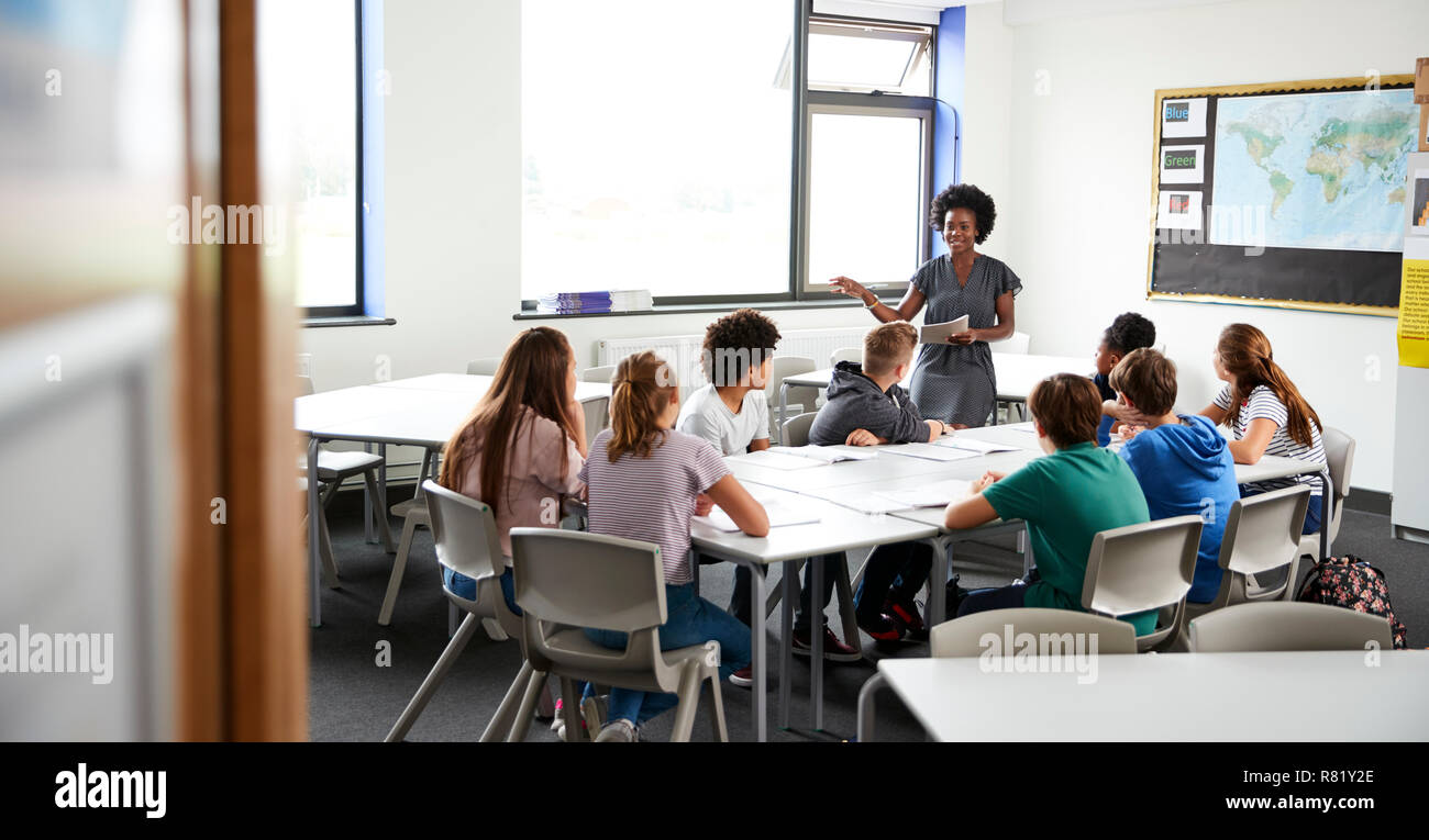 Female High School Tutor Standing By Table With Students Teaching Lesson Stock Photo