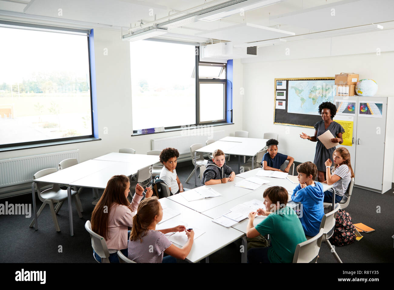 Female High School Tutor Standing By Table With Students Teaching Lesson Stock Photo