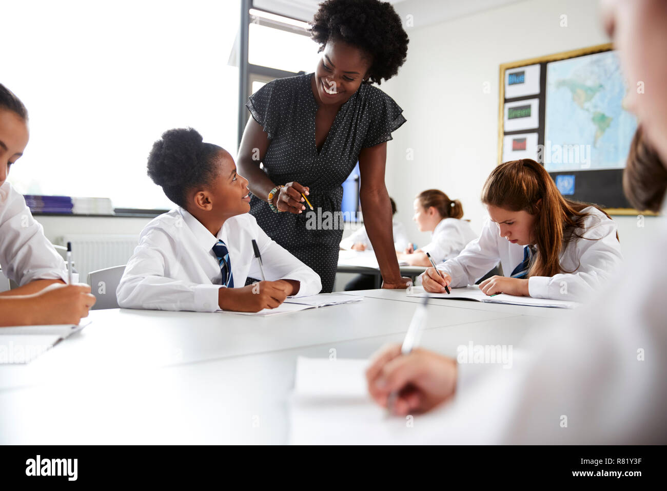 Female High School Tutor Helping Students Wearing Uniform Seated Around