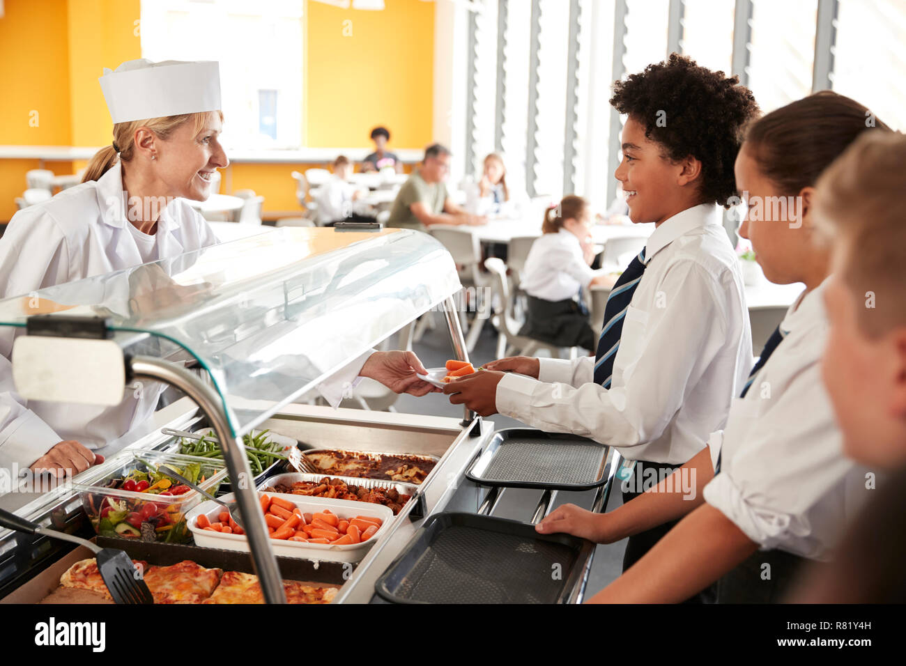 High School Students Wearing Uniform Being Served Food In Canteen Stock Photo