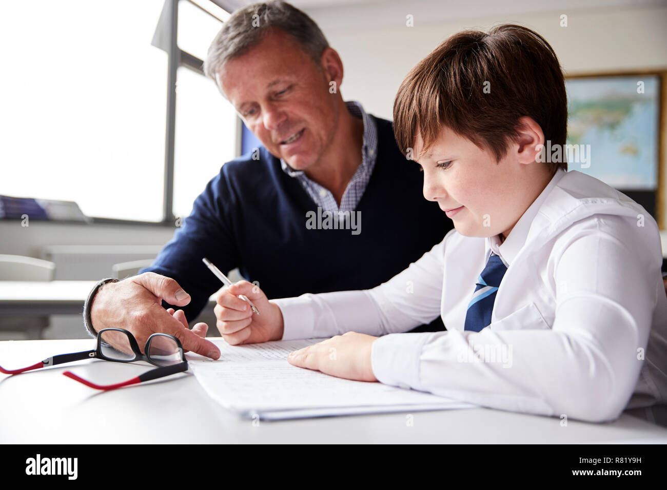 High School Tutor Giving Male Student Wearing Uniform One To One Tuition At Desk Stock Photo