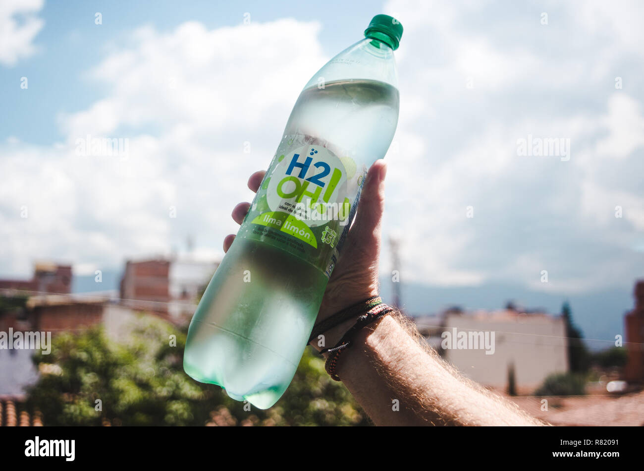 Male hand raises refreshing green bottle of Colombian flavored sparkling water brand, H2OH! in city of Medellín, Colombia Stock Photo