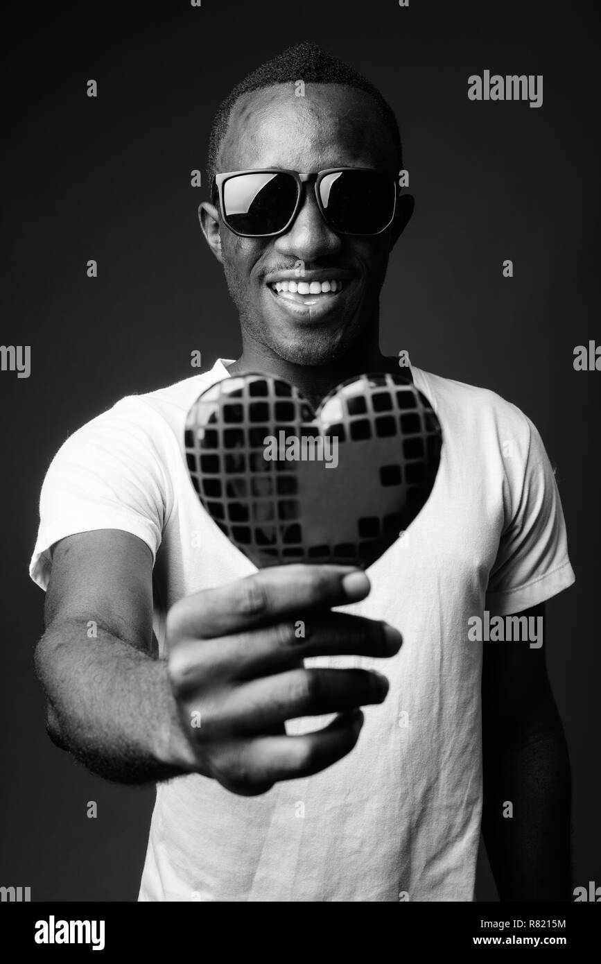 Young happy African man wearing sunglasses and holding heart Stock Photo