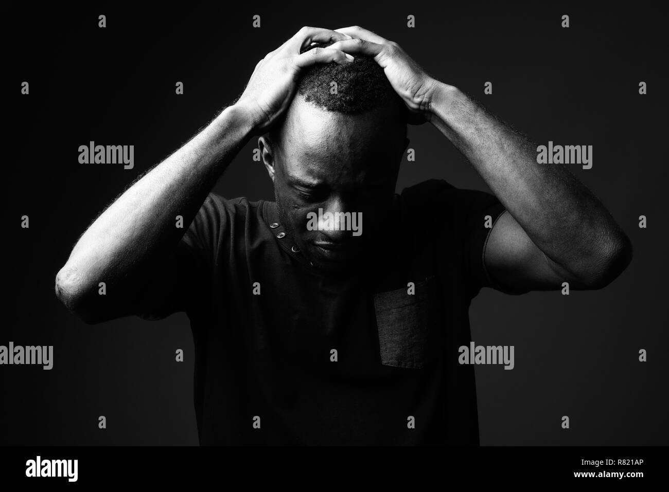 Sad young African man against black background in black and white Stock Photo