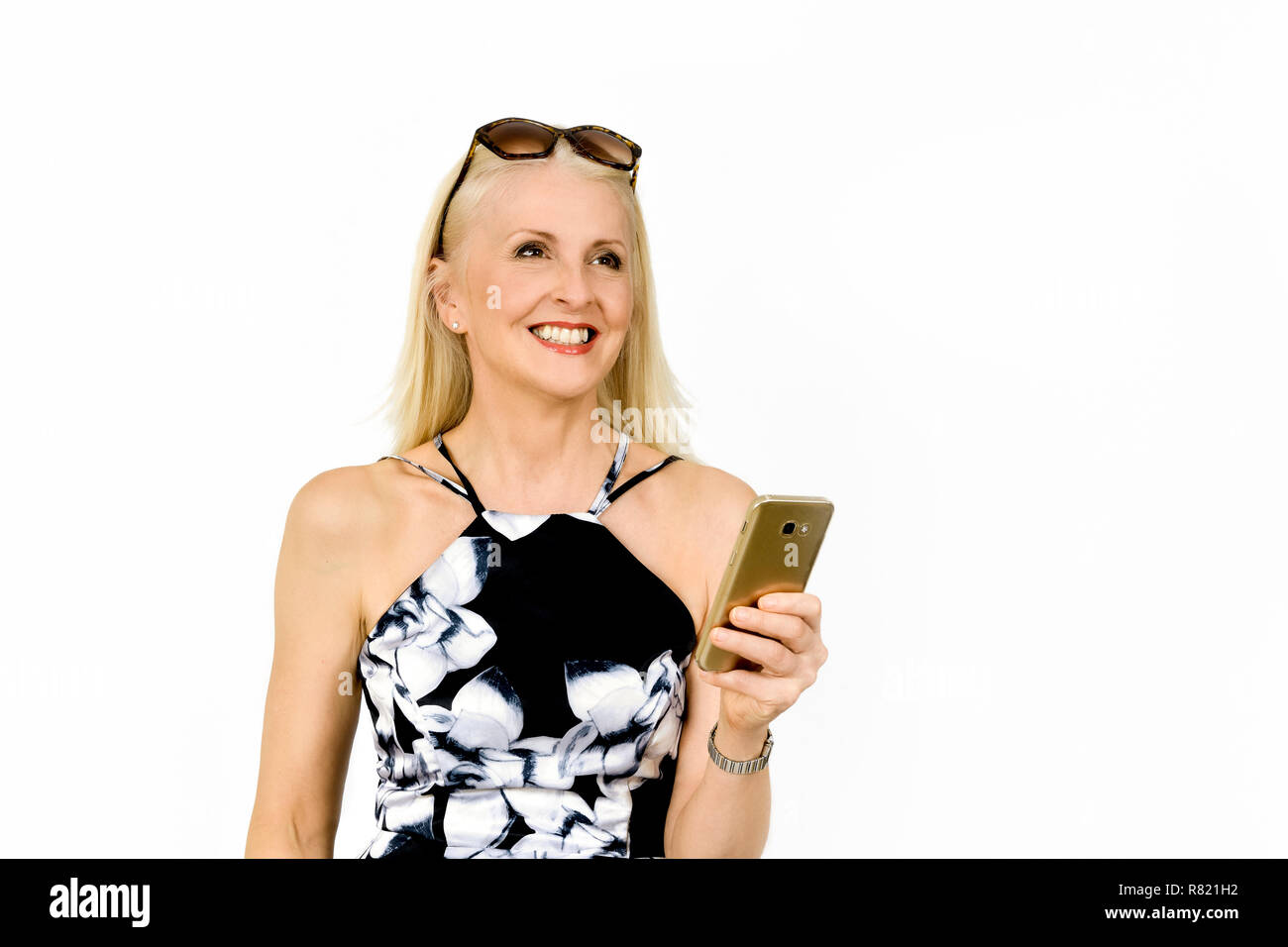 Attractive happy woman in pretty dress looking up after reading a text message, taken against white background Stock Photo