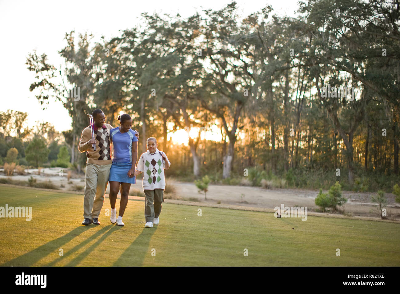 Family walking across golf course Stock Photo