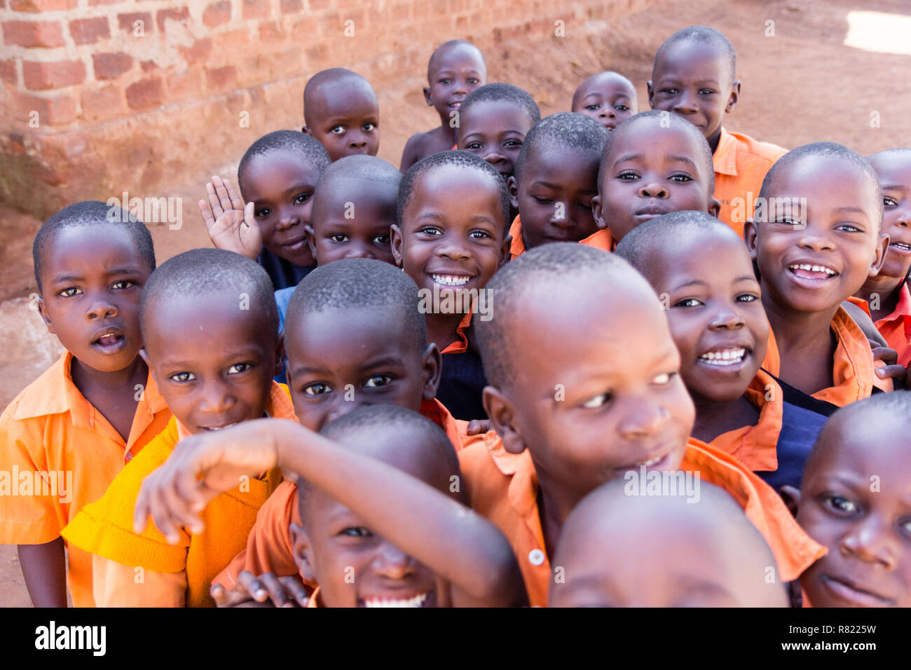 A group of happy primary-school children smiling, laughing and waving. They are dressed in school uniforms. Stock Photo