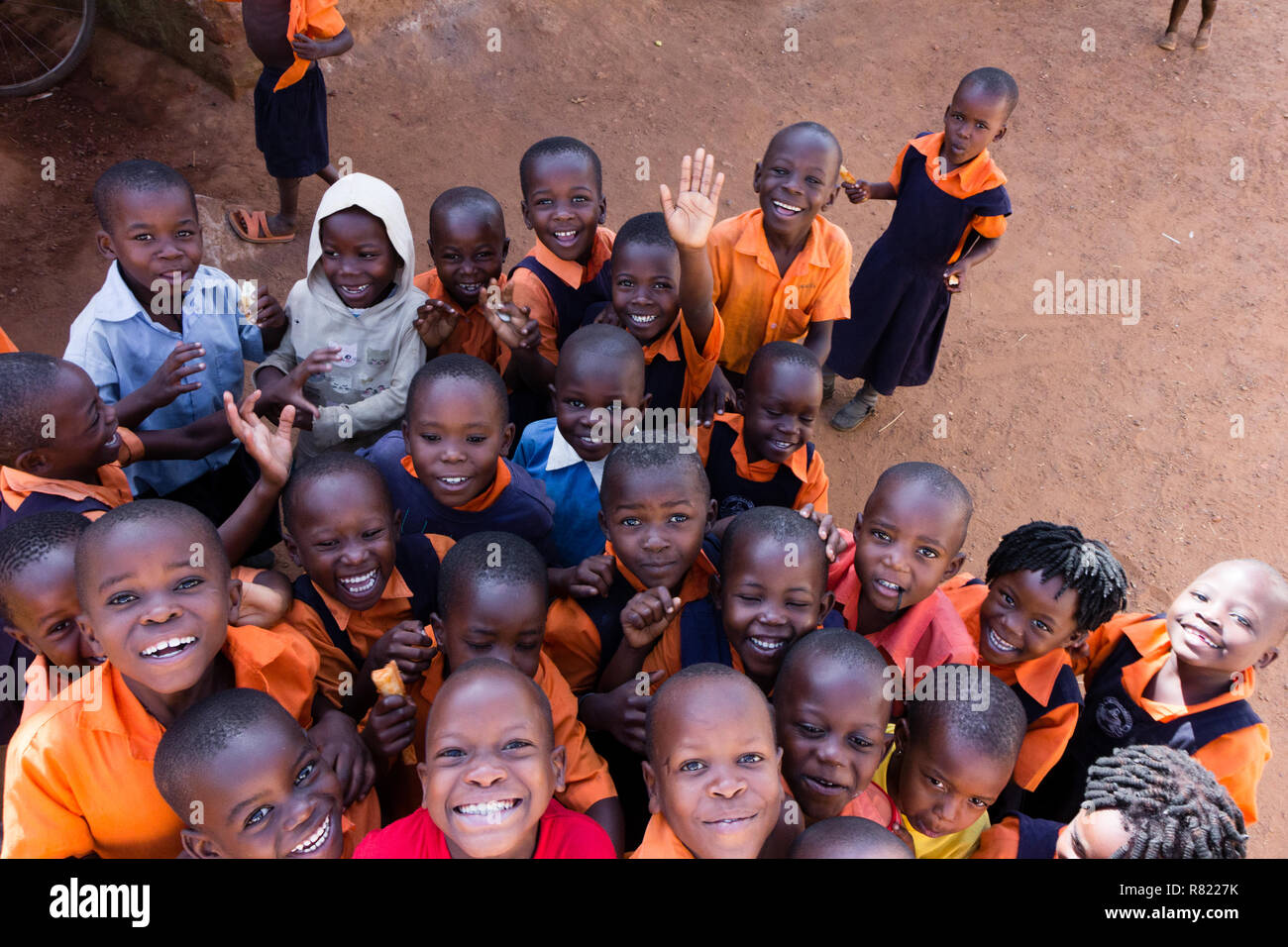 A group of happy primary-school children smiling, laughing and waving. They are dressed in school uniforms. Stock Photo