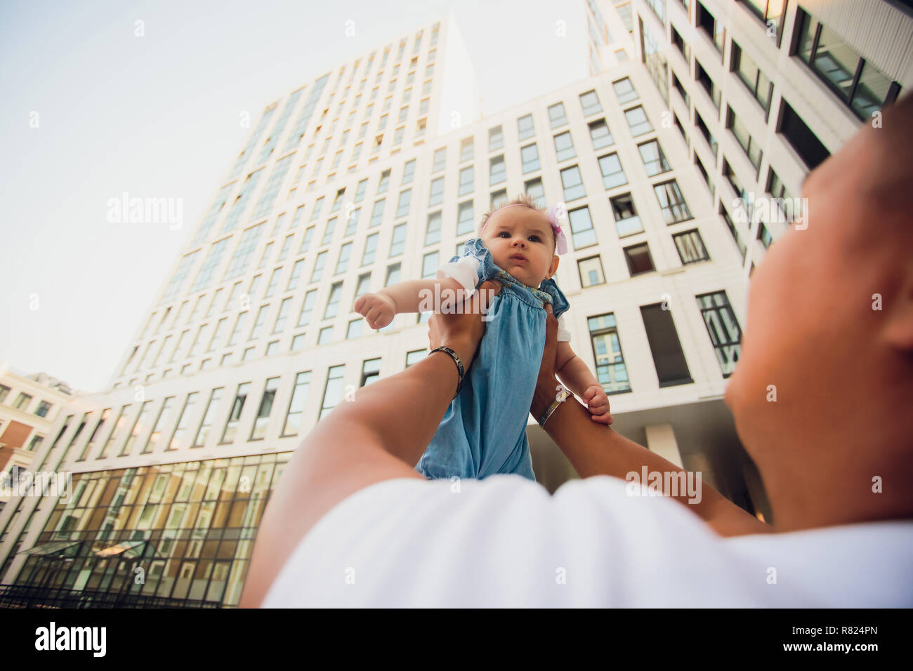 father holds his daughter on background skyscrapers. glass buildings. child on sky background Stock Photo