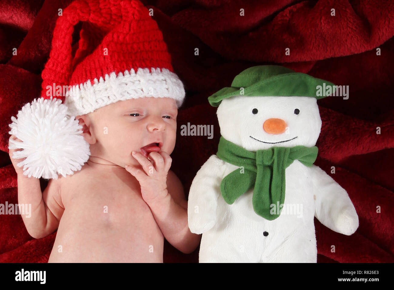 2 week old baby boy dressed as Santa with a snow man Stock Photo