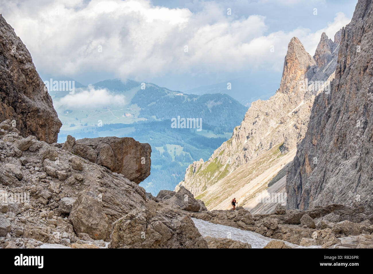 Rocky mountain canyon with a scenic view to a valley in the alps with a mountain wanderer Stock Photo