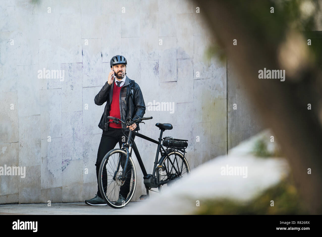 Businessman commuter with bicycle walking home from work in city, using smartphone. Stock Photo