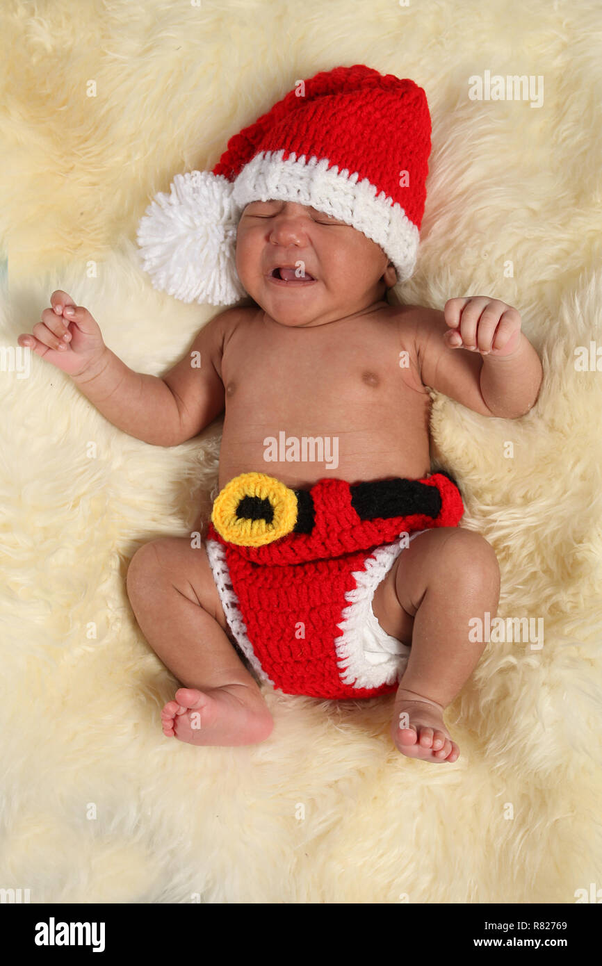 mixed race new born baby boy dressed as Santa Crying Stock Photo