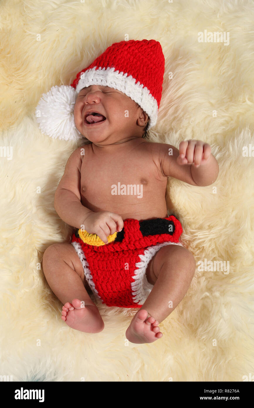 mixed race new born baby boy dressed as Santa Crying Stock Photo