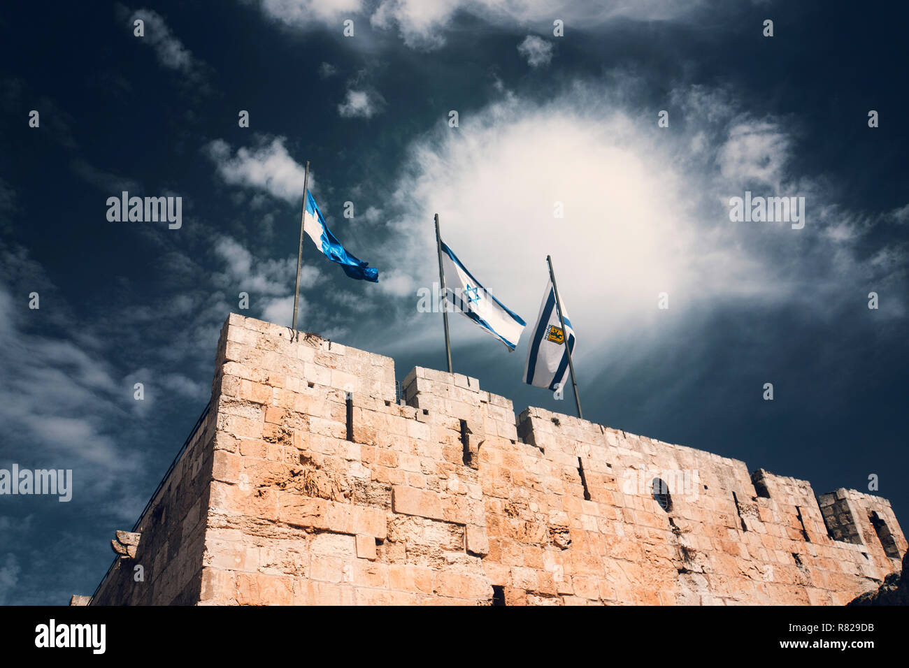 Israel and Jerusalem flags on Jerusalem old city walls against the blue sky with white clouds in the Sunny summer light Stock Photo