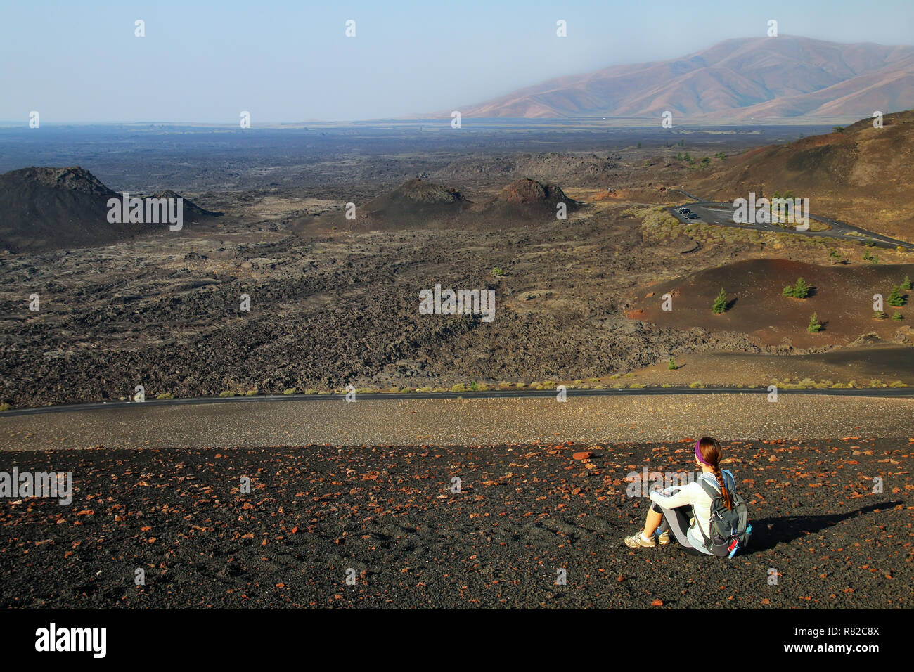 Woman sitting on the top of Inferno Cone, Craters of the Moon National Monument, Idaho, USA Stock Photo