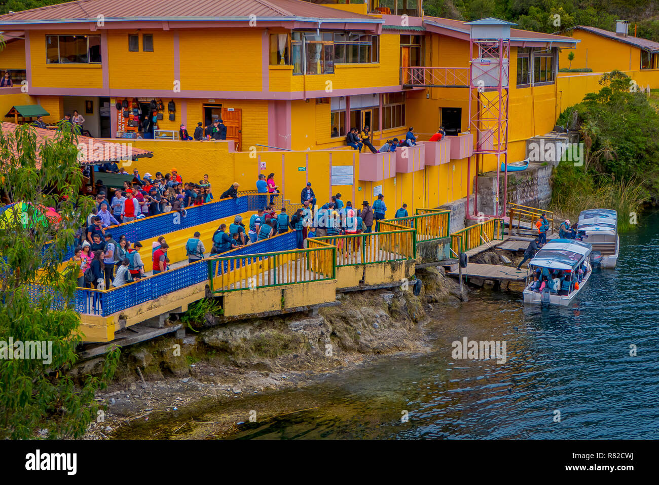 CUICOCHA, ECUADOR, NOVEMBER 06, 2018: Above view of yellow information building with some tourists boarding a boat to have a tour in the Cuicocha lake in Ecuador Stock Photo