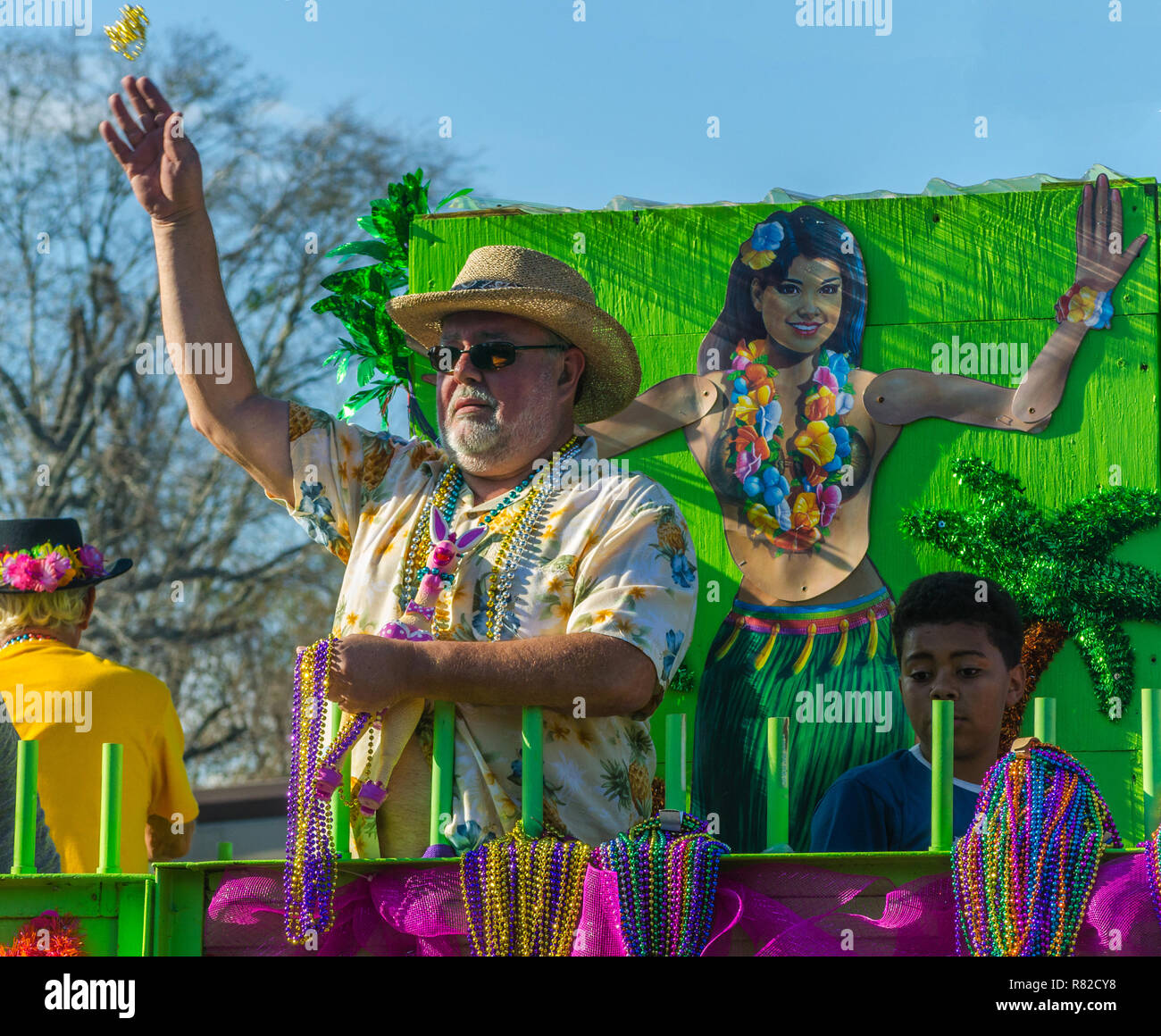 A reveler throws Mardi Gras beads to the crowd as his float travels