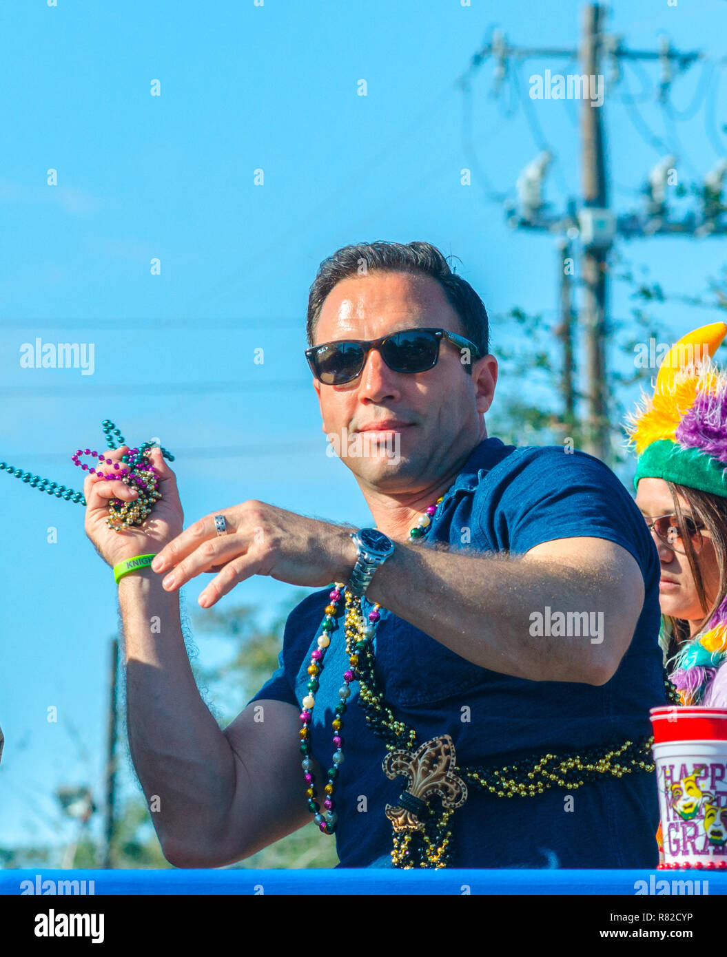 A reveler throws Mardi Gras beads to the crowd as his float travels