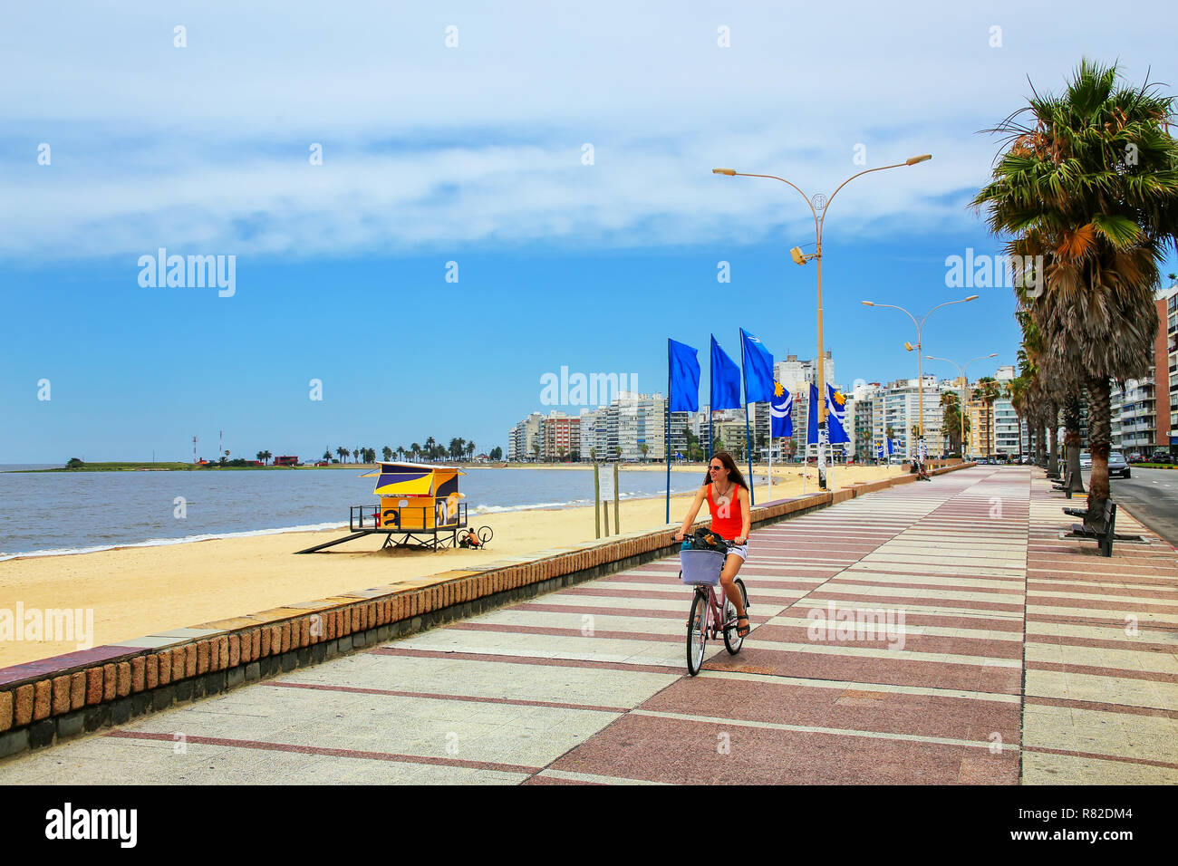 Woman biking on the boulevard along Pocitos beach in Montevideo, Uruguay. Montevideo is the capital and the largest city of Uruguay Stock Photo