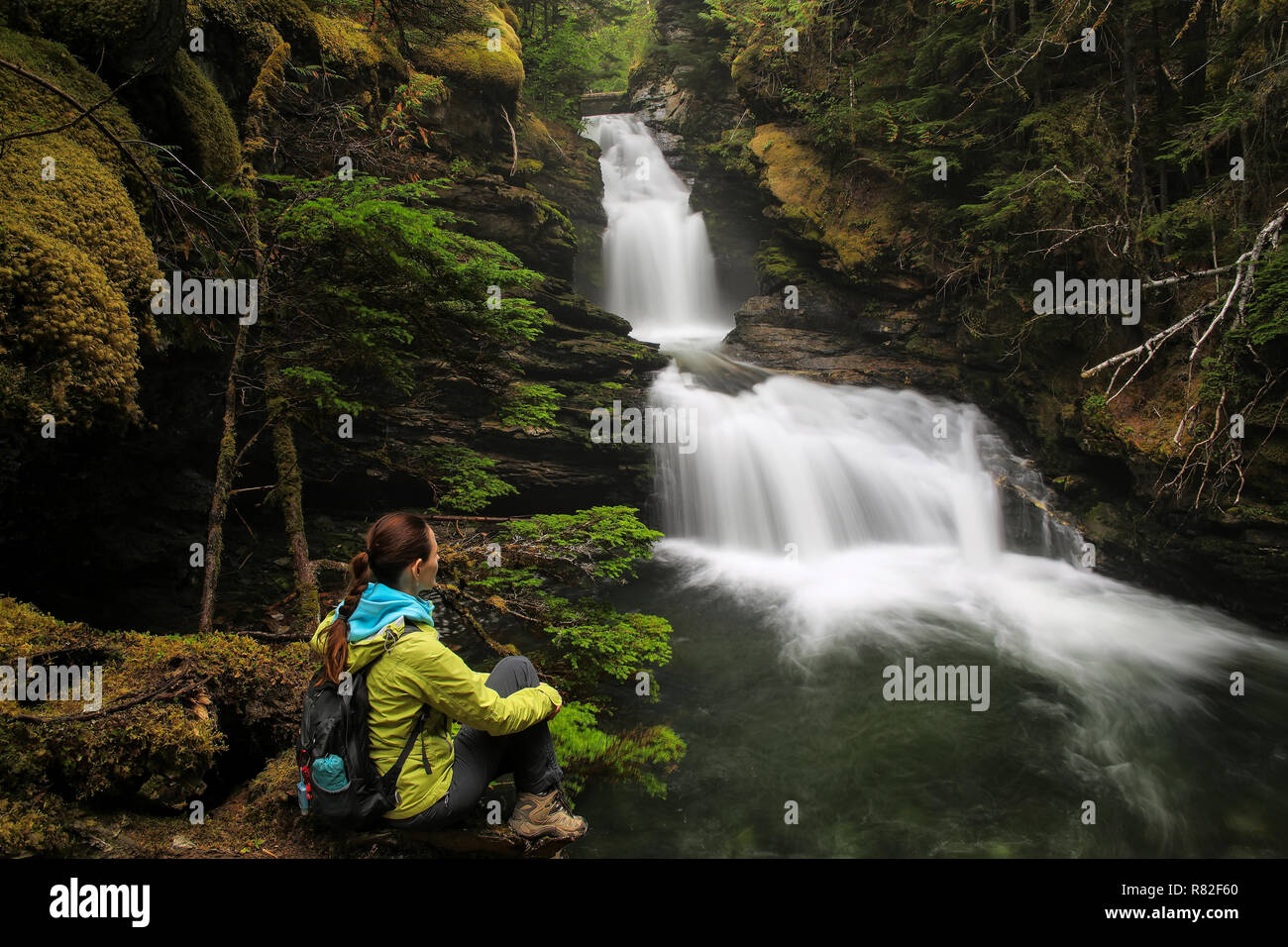 Young woman sitting by Sticta Falls in Wells Gray Provincial Park, British Columbia, Canada. It is fourth largest park in British Columbia. Stock Photo