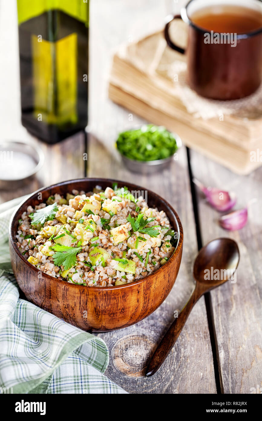 Buckwheat porridge with marrow, chives, salty cucumber and coriander on the wooden table Stock Photo