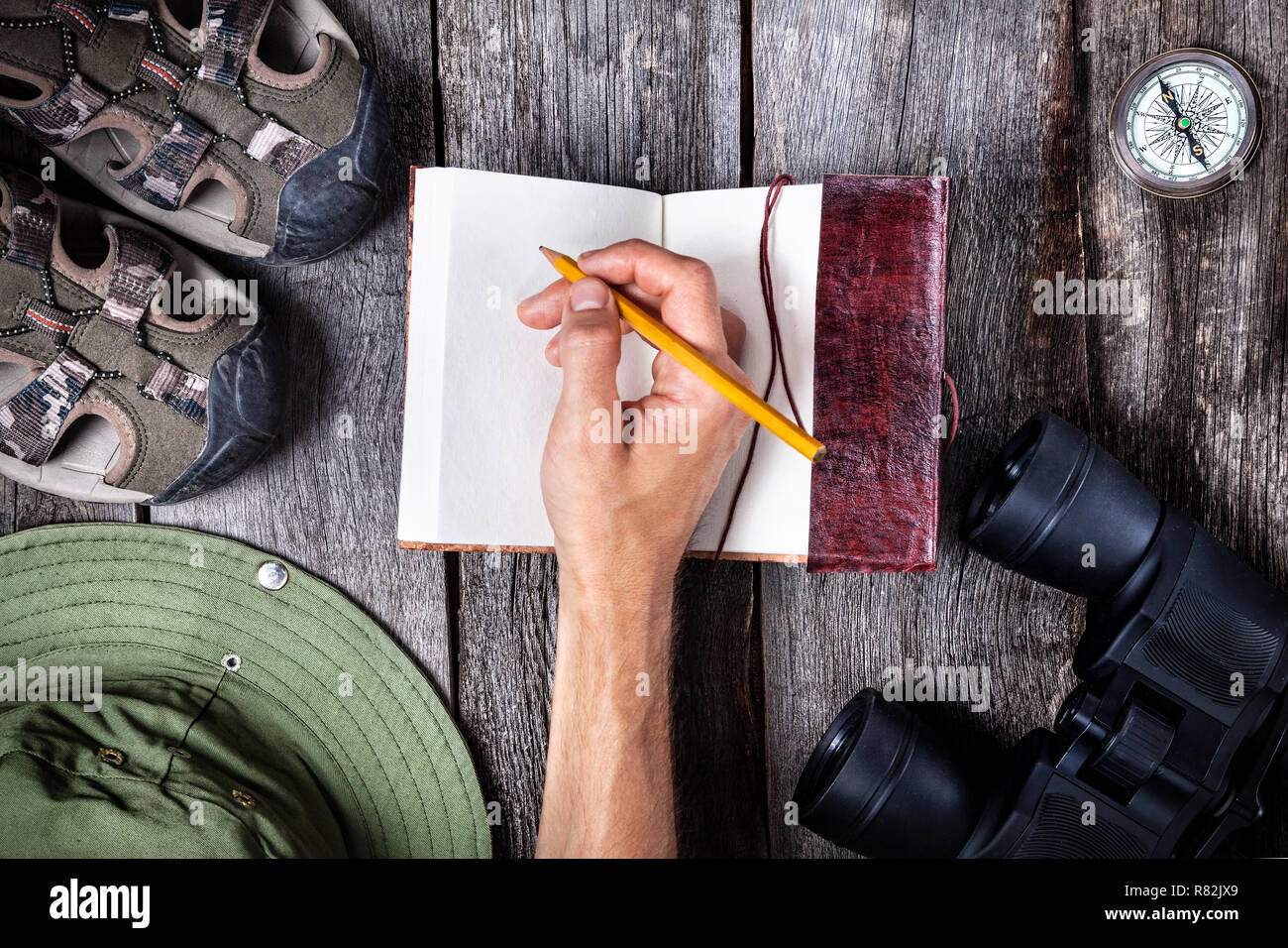 Man writing in the notebook on the wooden table with traveler outfit Stock Photo