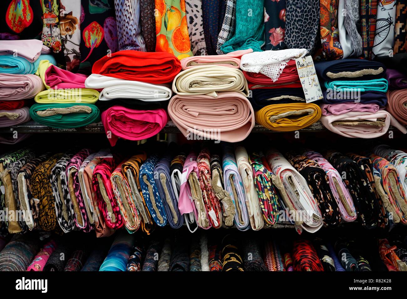 Colourful fabric piled neatly at a stall in Leicester market Stock
