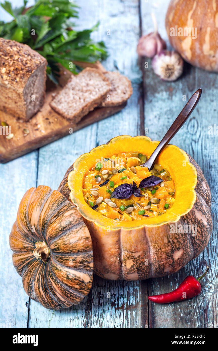 Soup with lentil decorated in the carved pumpkin on the blue wooden background at autumn holidays Stock Photo