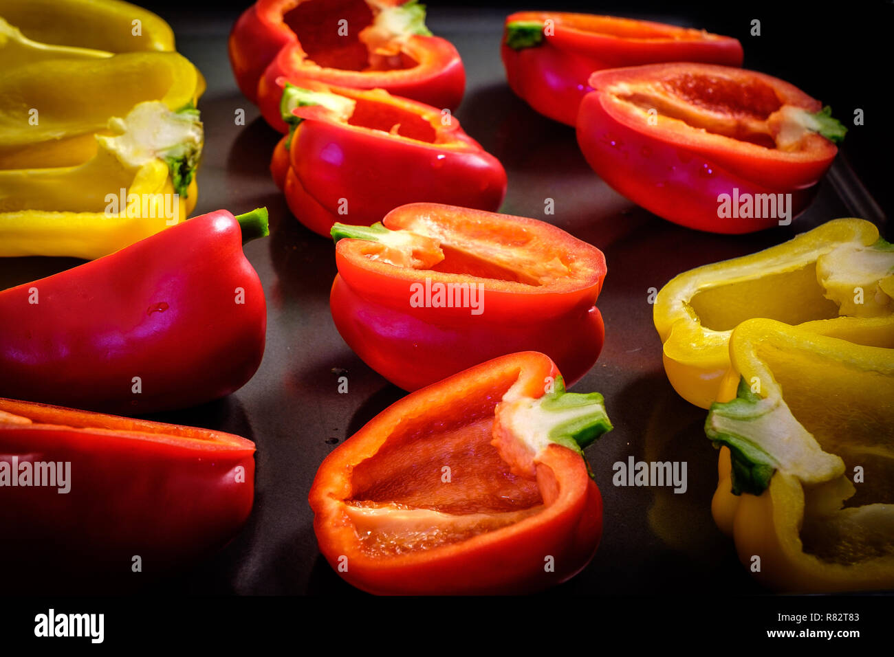 Red and yellow bell peppers cut in half on dark background Stock Photo ...