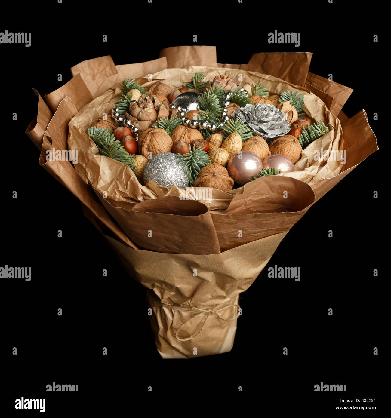 Beautiful Christmas decorative bouquet of various nuts, decorated with twigs of Christmas tree and balls on black background Stock Photo