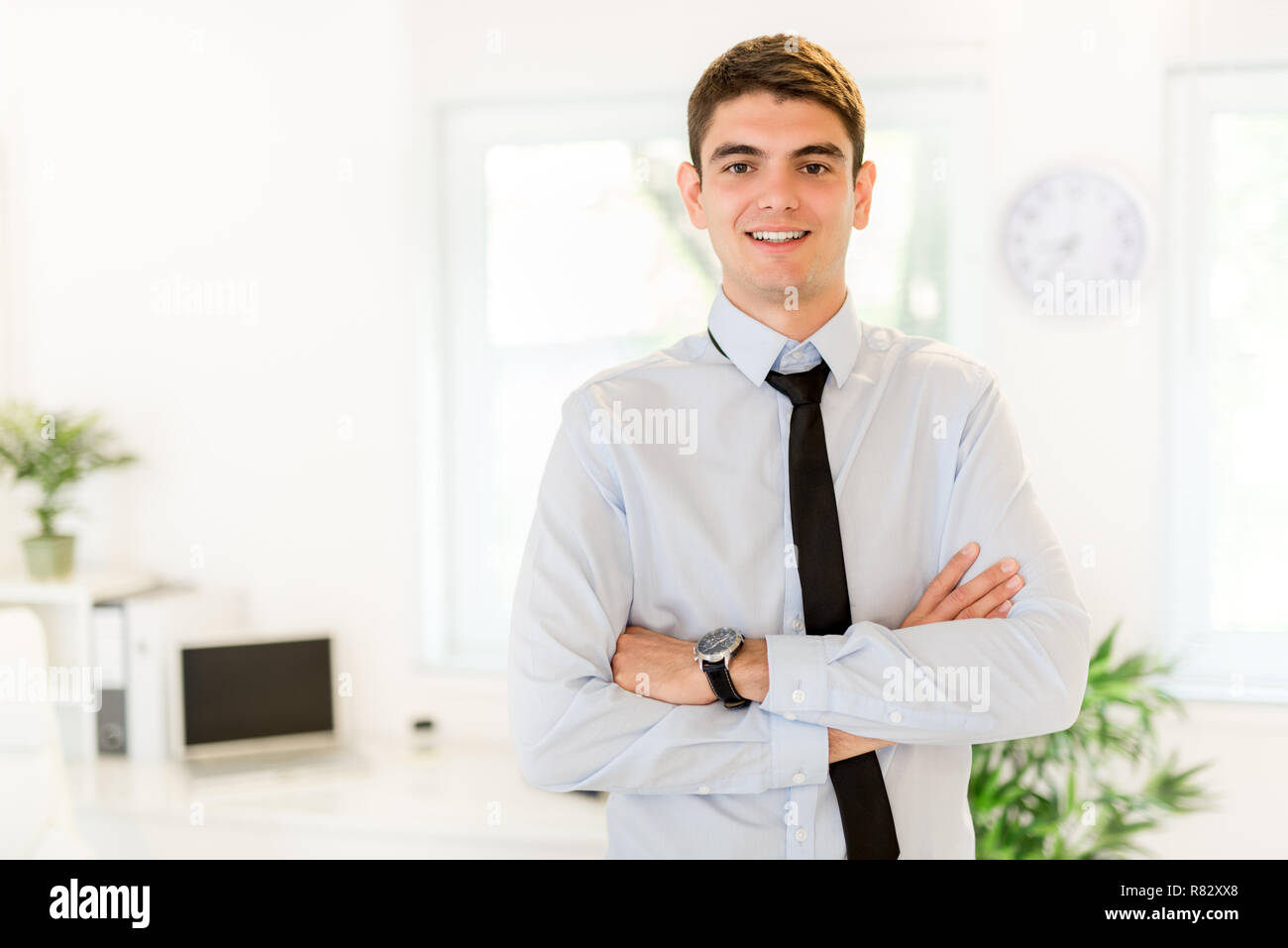Young successful businessman standing in the office with arms crossed ...