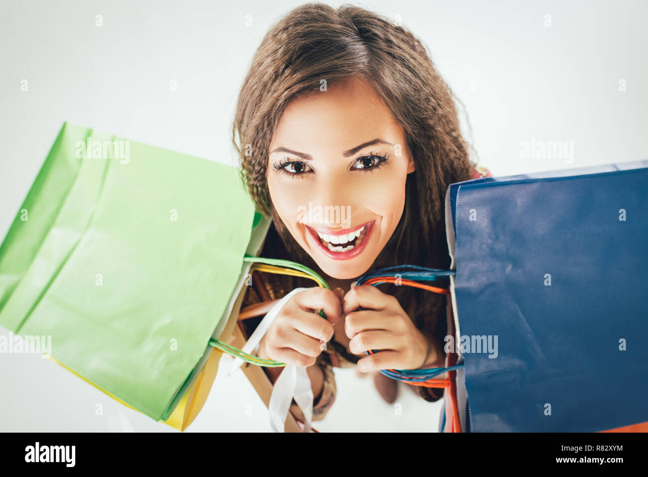 Beautiful cheerful woman with many shopping bags. Looking at camera