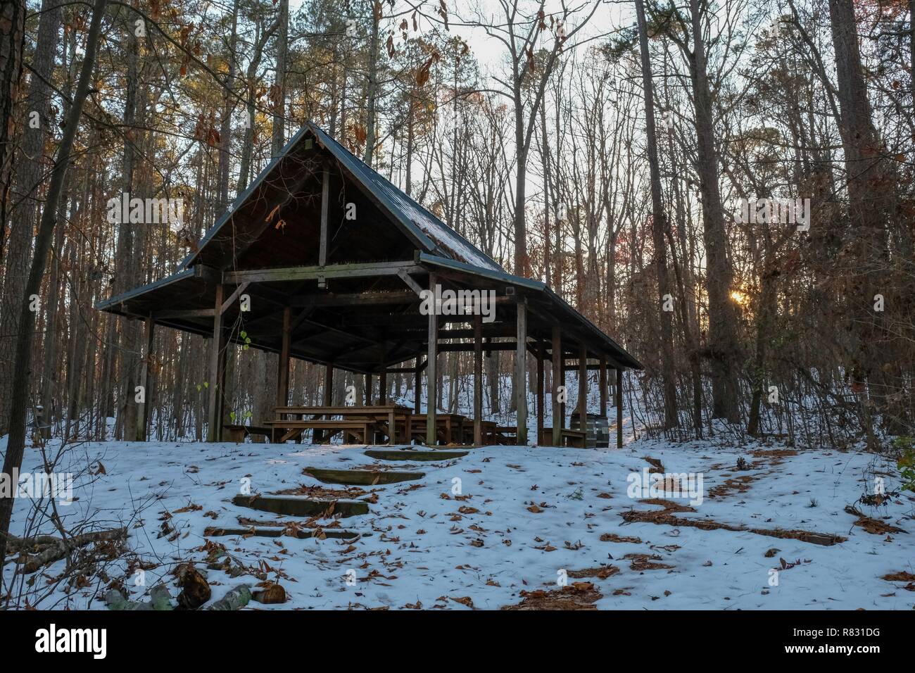 The fading sun peeks at an outdoor classroom nestled in the woods with the remnants of snow on the ground at Yates Mill County Park in Raleigh. Stock Photo