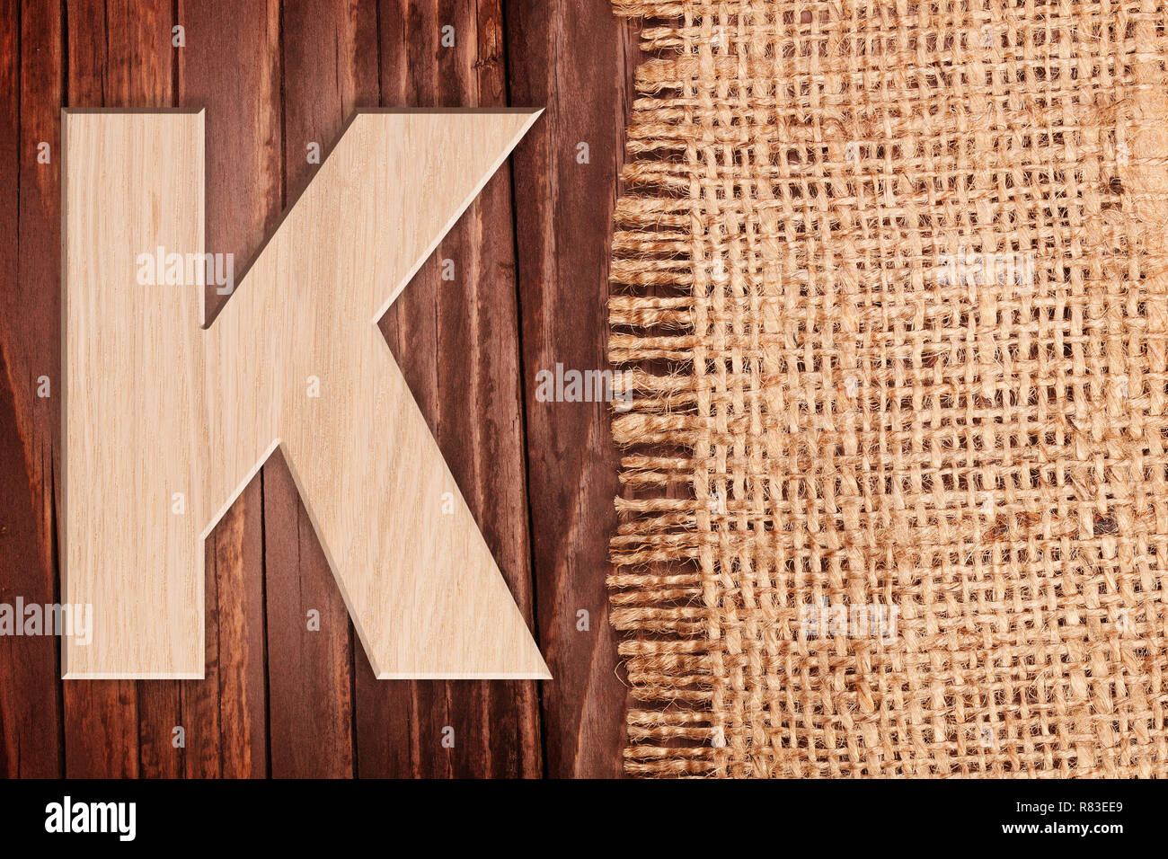 Wooden alphabet letter symbol - K. On wooden table background wih burlap Stock Photo