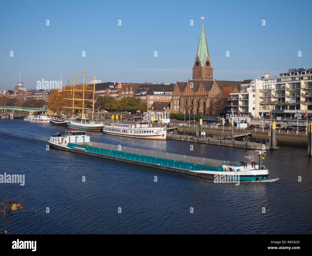 Bremen, Germany - November 17th, 2018 - River Weser with historic waterfrontm moored ships and cargo vessel passing by Stock Photo
