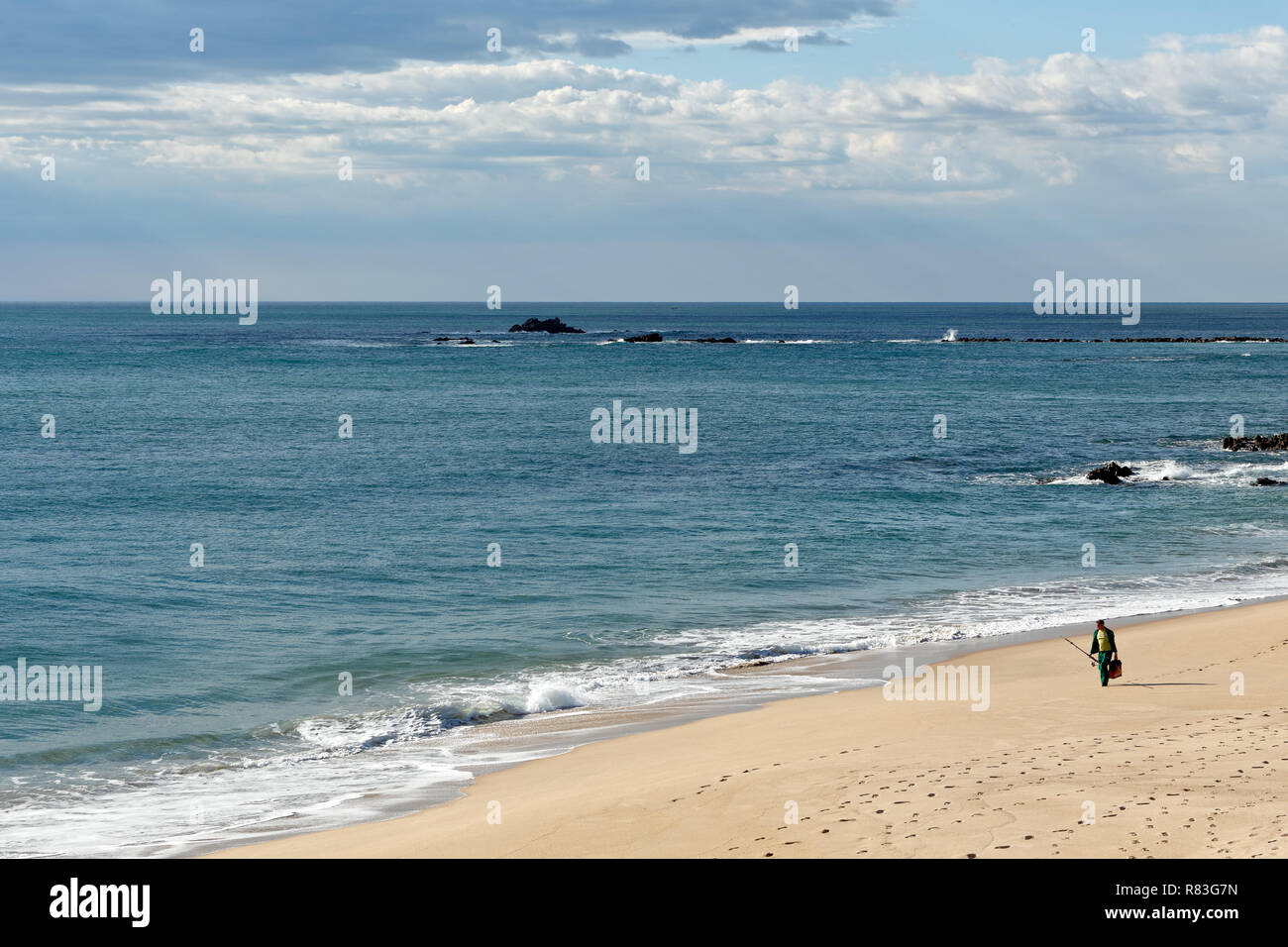 Vila do Conde; Portugal: March 19; 2015: Early spring on a portuguese northern beach with beautiful blue sea and sky, seeing a fisherman walking on th Stock Photo