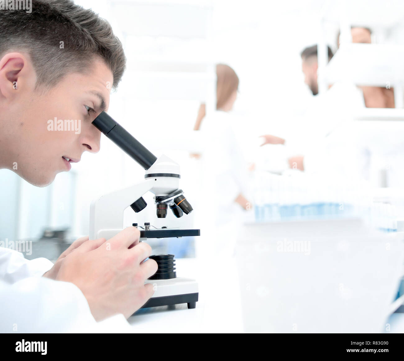 male research scientist looks at biological samples under micros Stock Photo
