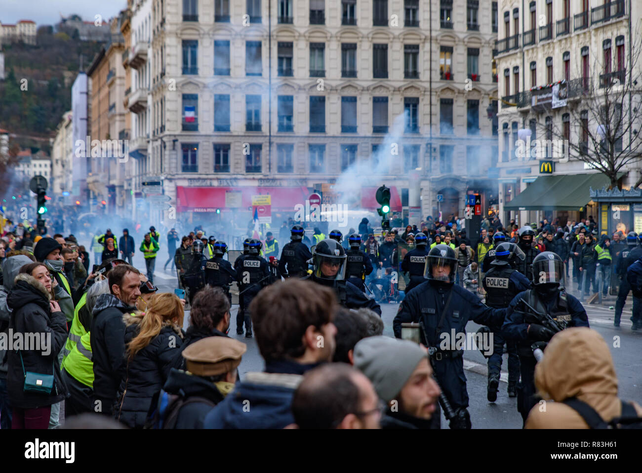 French riot police firing tear gas at Yellow Vests (Gilets Jaunes) protesters against fuel tax, government, and French President Macron. Lyon, France. Stock Photo