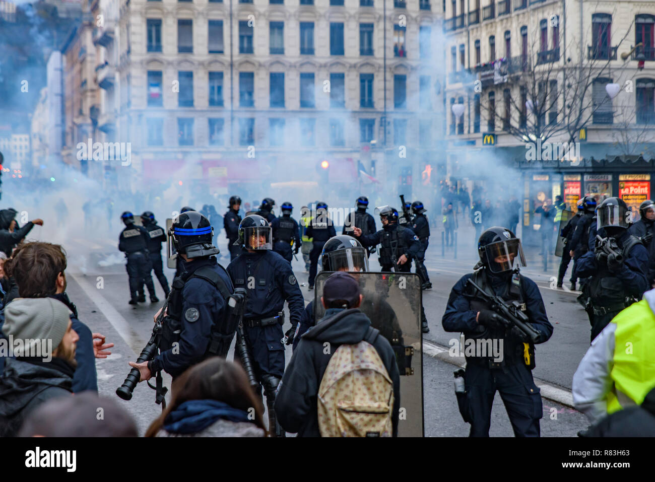 French riot police firing tear gas at Yellow Vests (Gilets Jaunes) protesters against fuel tax, government, and French President Macron. Lyon, France. Stock Photo