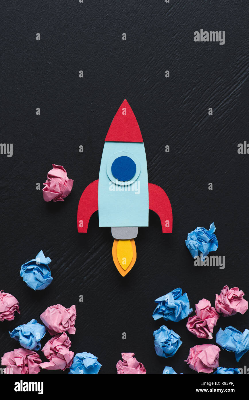 Paper Rockets Pink cardboard rocket with pink and blue crumpled paper balls on black ...