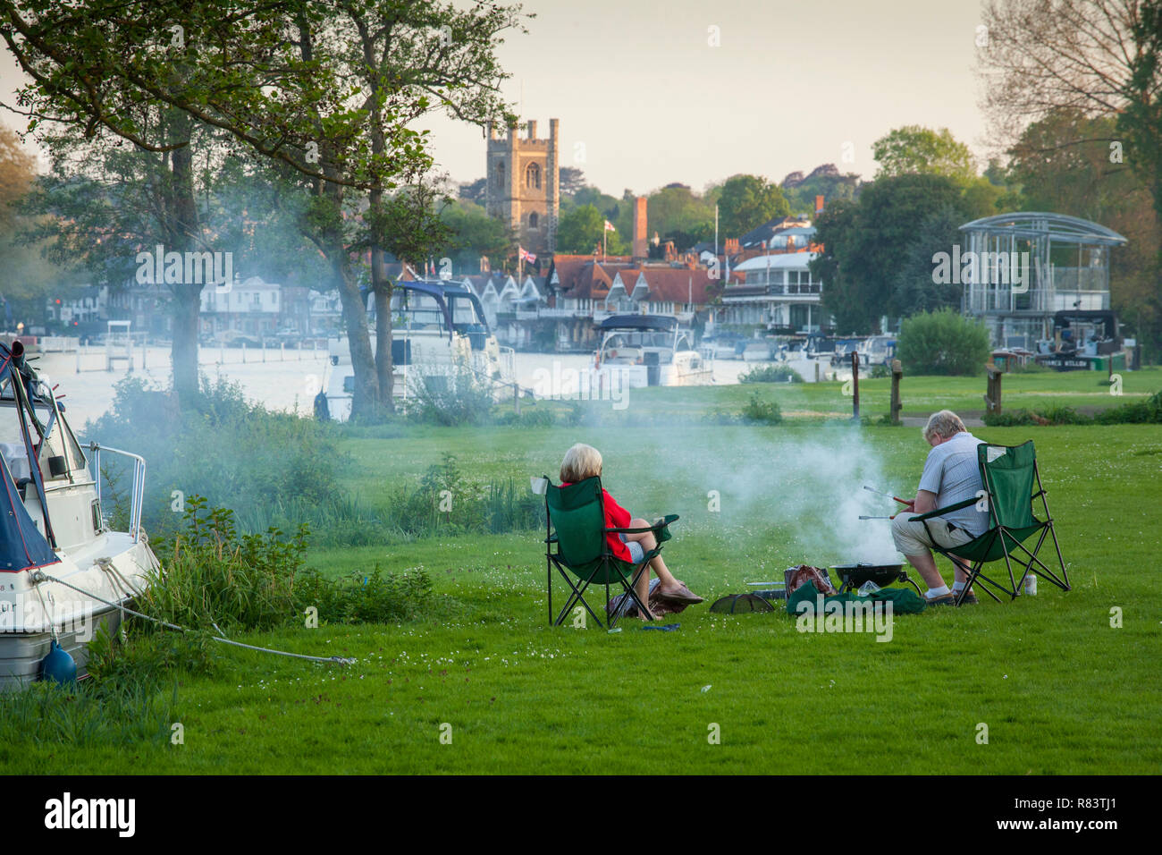 A couple enjoy a peaceful Summer barbecue or barbeque by their boat on ...